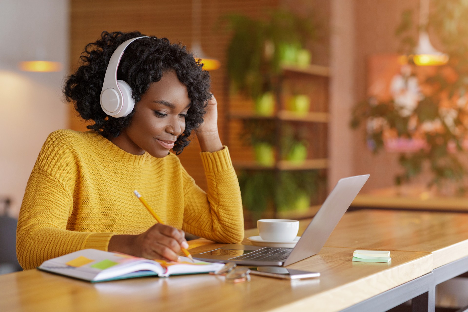 Smiling black girl with headset studying online, using laptop